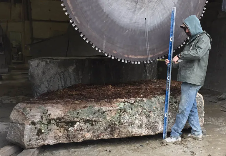 Man with giant saw cutting stone block