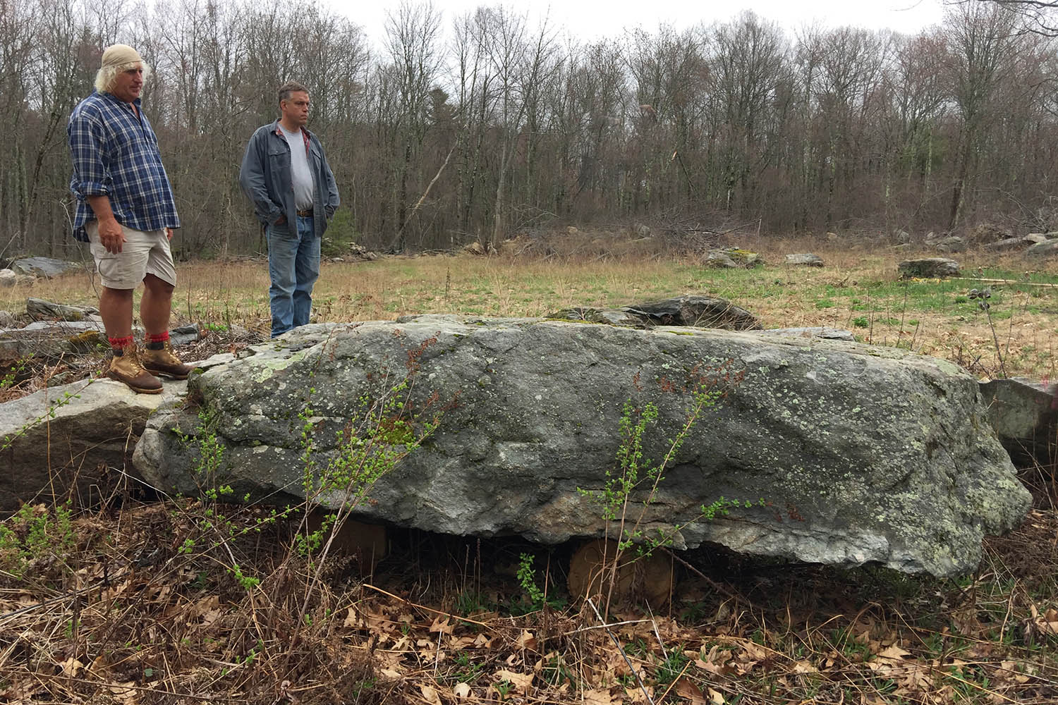 Two workers standing on giant fieldstone ledge